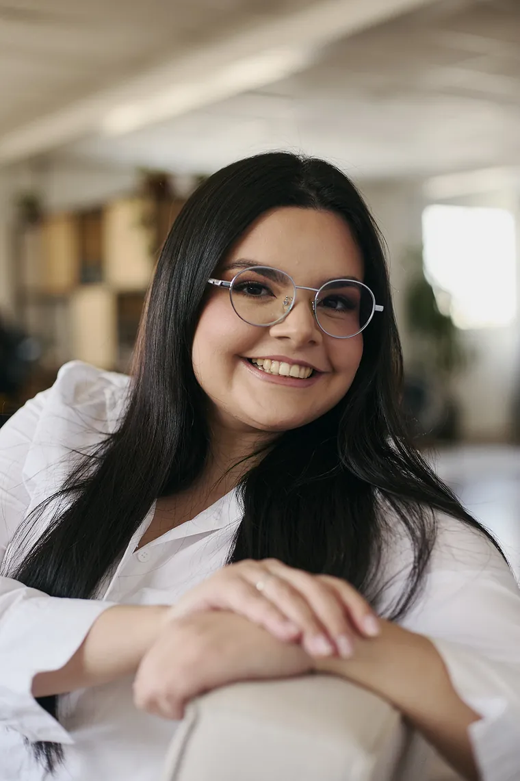 Jennifer da Luz Silva sorrindo, apoiada no encosto de uma poltrona